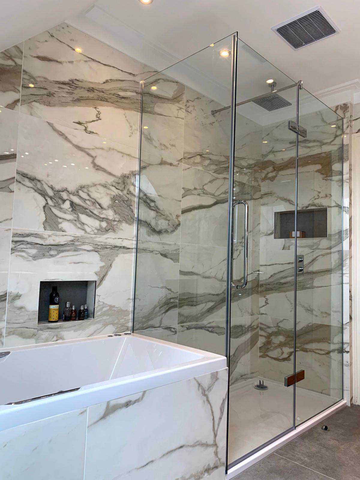 Frameless glass bath screen with marble tiling, London